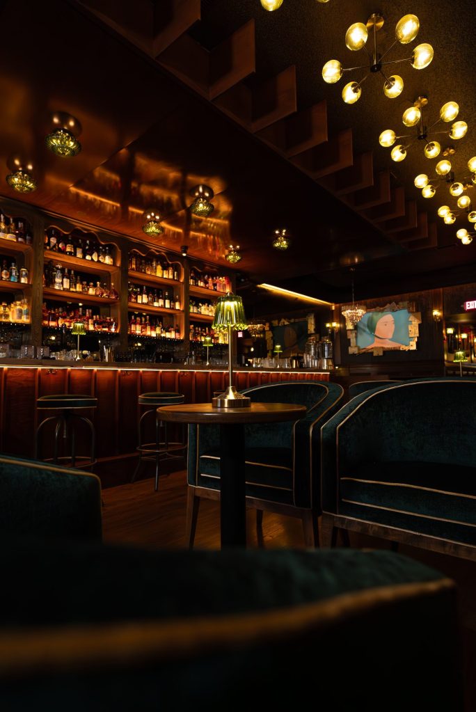 Side view of the bar, velvet lounge chairs and brass lamps